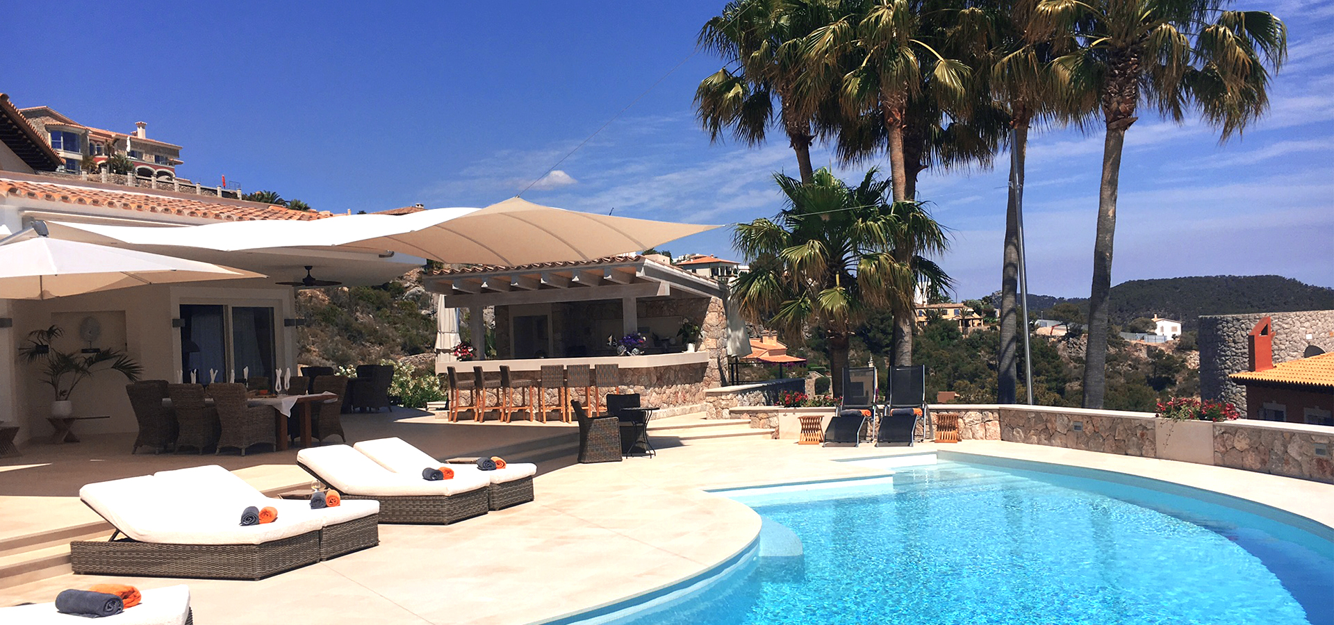 Bild: Außenbereich in Mallorca mit Pool, Palmen, Liegen und einer Bar.